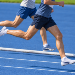 青い陸上トラックを走る短距離選手